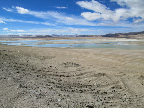 Vast arid land with a small body of water under a blue sky