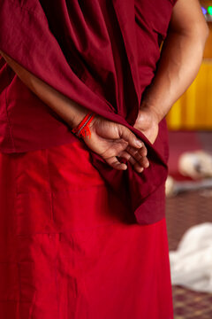 Hands of a monk in a red robe clasped behind his back, Ladakh, Leh, India