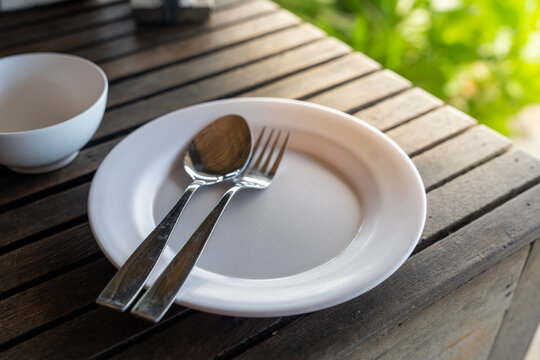 Plates, spoons, and forks placed on a wooden