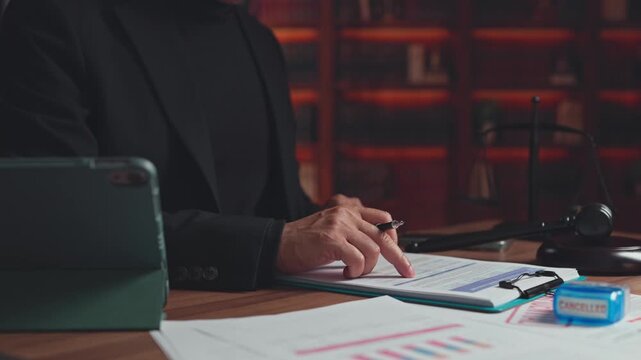 Lawyer reviews paperwork beside stamp, gavel, tablet inside law office. Contract cancellation process, commercial legal consultation, corporate compliance audit, regulatory paperwork review.