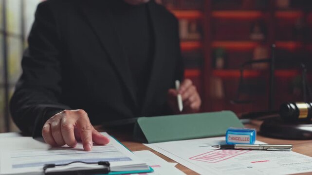Lawyer reviews confidential contract documents beside digital tablet in office. Legal dispute arbitration, contract cancellation procedure, regulatory compliance lawsuit audit.