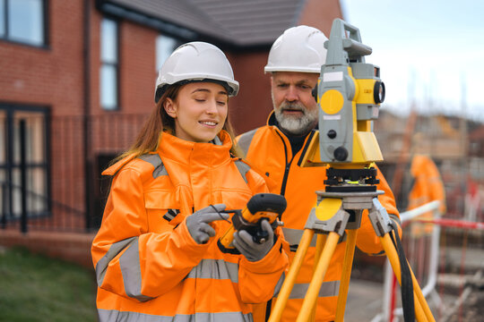 Surveyors operate a total station at a building site