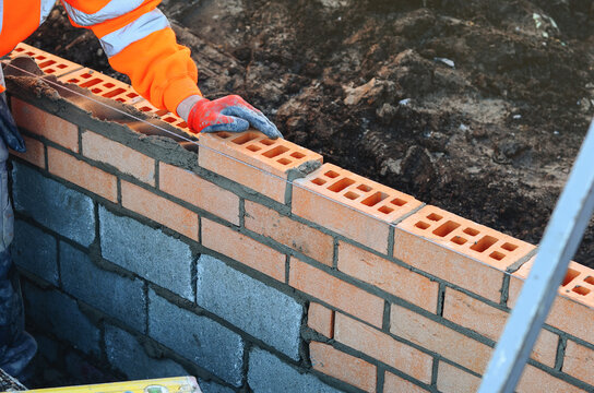 Construction worker laying bricks to build a wall at a work site