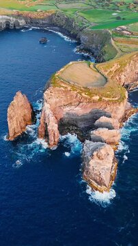 Sea stacks and rocky headland on Sao Miguel, Azores, Portugal, with Atlantic Ocean. Aerial footage of coastal rock formations and steep cliffs beside island shore