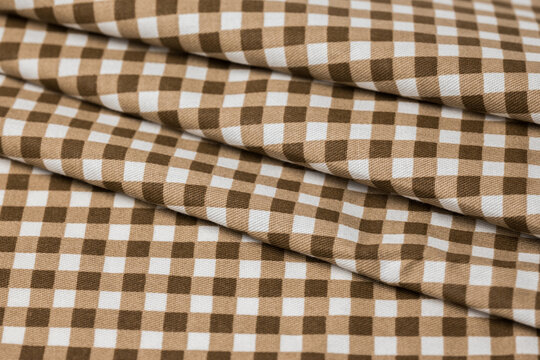 Brown and white gingham fabric with woven checks and layered folds