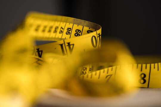 Yellow measuring tape curling in close-up for body and length measurement
