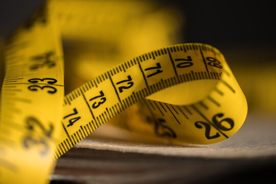 Yellow measuring tape curling in close-up with scale markings