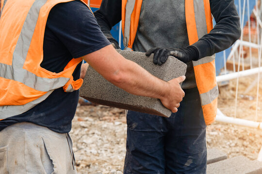 Construction workers carrying a concrete block at an outdoor work site