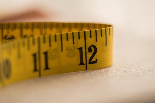 Yellow measuring tape curling around the twelve-inch mark