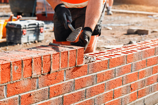 Construction worker laying bricks to build a wall at a worksite