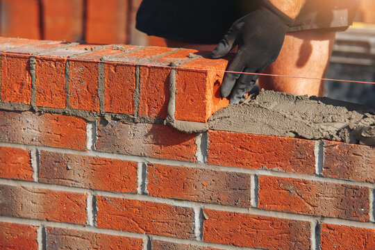 Bricklayer placing a brick on a wall at a construction site