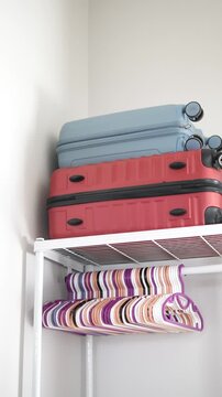 Vertical medium shot of luggage suitcases stacked on closet shelf for home organization