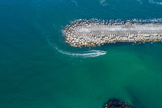 Boat leaving a wake around a curved breakwater The Concept of maritime journey