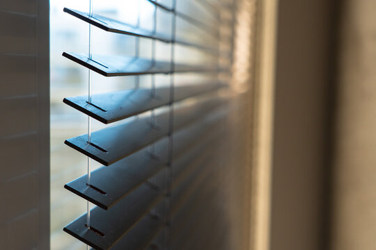 Close-Up of Dark Horizontal Window Blinds with Soft Natural Light and Warm Shadows