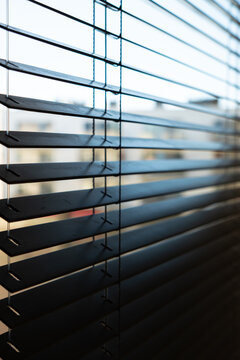 Close-Up of Dark Horizontal Window Blinds with Soft Natural Light and Warm Shadows