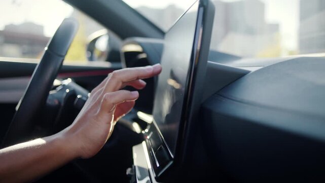 Female hand touches dashboard screen inside modern car cabin