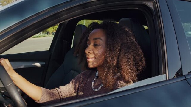 Smiling woman lowers car window happily looking to camera