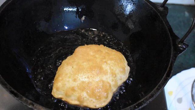 Homemade puris frying in hot oil 