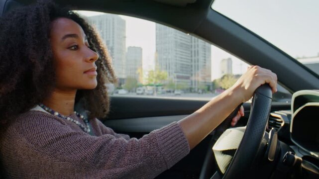 Calm woman drives modern car while watching urban road ahead