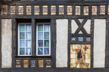 Detail of an old medieval wall, typical of Picardy, featuring half-timbering and painted earthenware tiles, in the town of Gerberoy in France © sissoupitch