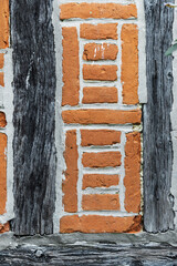 Texture of an old medieval wall, typical of Picardy, featuring half-timbering and red bricks, in the town of Gerberoy in France © sissoupitch