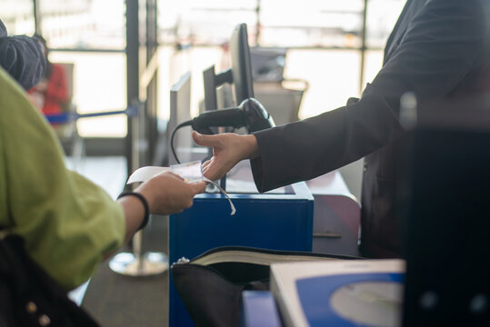Close up of passenger handing boarding pass and ID card to airline staff at airport boarding gate counter