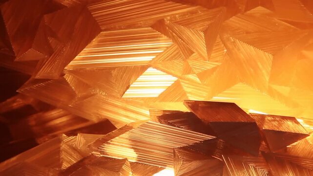 Layered orange geometric shapes form a glowing abstract pattern in a bright setting