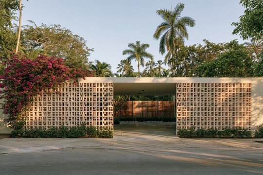 Tropical modern house with breezeblock walls and shaded carport in lush garden setting