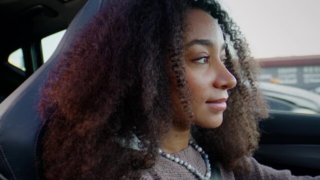 Woman with kinky hair drives car on city streets in rush hour