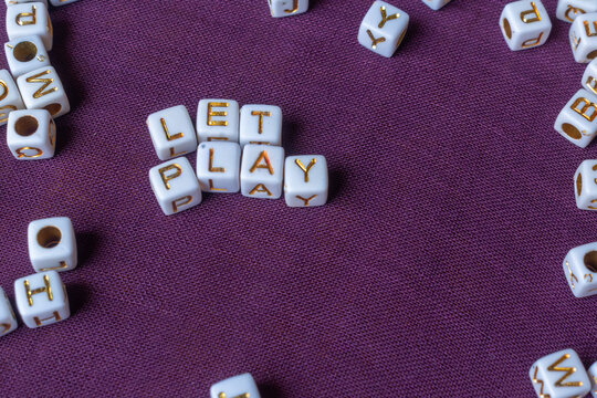 White alphabet beads spelling let play on purple fabric texture background for education.