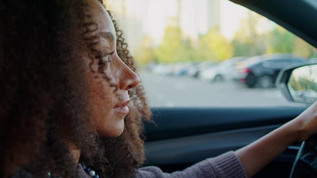 Young woman drives modern sedan through lively city center