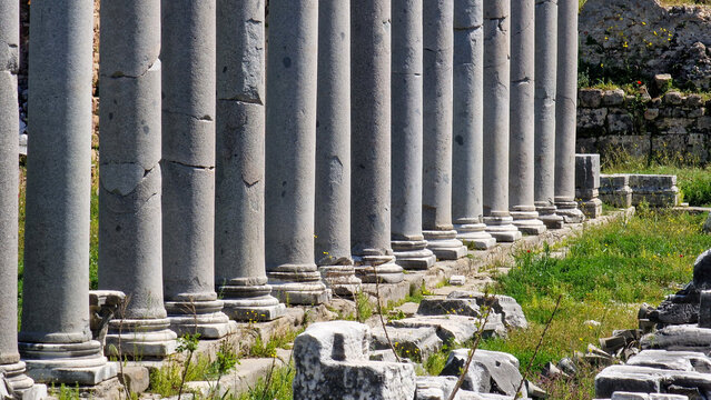 Long perspective colonnade of ancient fluted granite pillars along archaeological street in antique Roman city. Classical Mediterranean antiquity ruins.