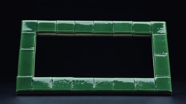 Green ceramic tiles form a rectangular frame on a dark surface in a still composition