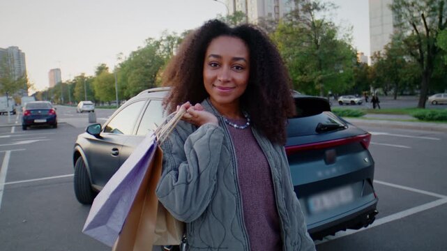 Cheerful woman smiles warmly holding colorful shopping bags