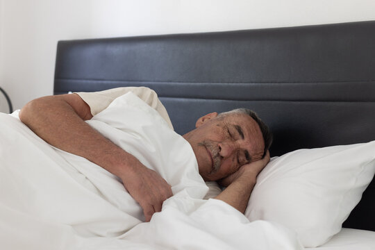 senior man sleeping in bed at home