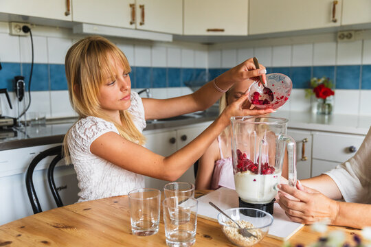 Girl Adding Frozen Berries to Blender for Healthy Smoothie