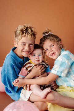 Big brother and sister snuggling with baby sibling