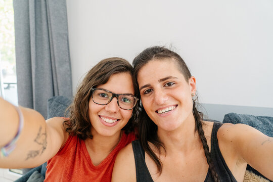 Happy lesbian couple taking selfie indoors
