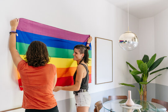 Lesbian couple proudly decorating home with rainbow flag