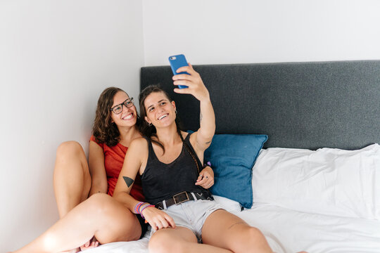 Lesbian couple taking a selfie in bed