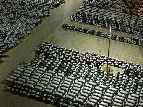 New cars parked in a large industrial storage facility at night