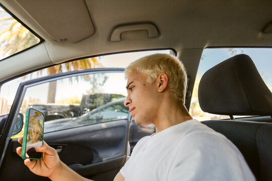 Man Sits in Car While Taking Selfie With Phone