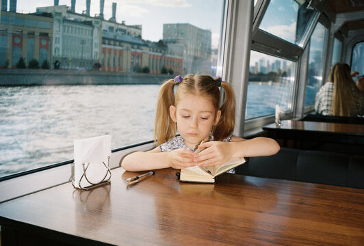 A child looks up mid-sketch as the city drifts past