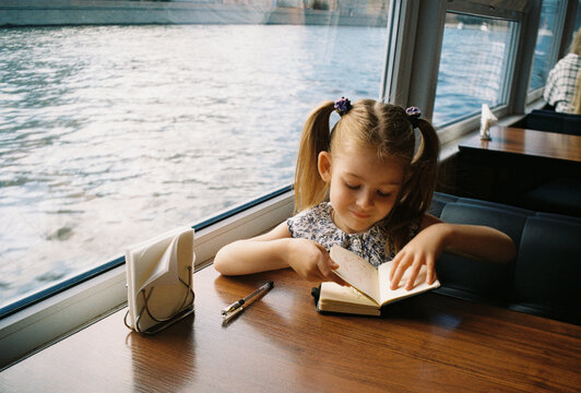 A girl draws in her notebook aboard a river cruise