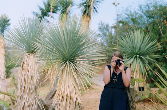 Woman takes a picture in a desert area with cacti