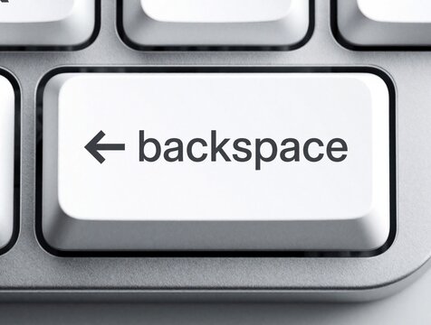 Close up macro view of white backspace key on modern silver computer keyboard. Single button for delete undo command in office work. Minimalist hardware detail of typing device for correcting text