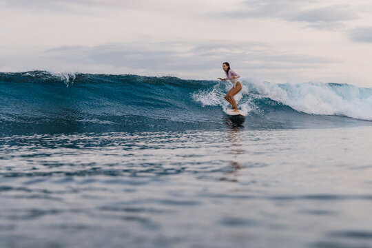 Surfer woman riding on wave on surfboard in ocean, during surfing