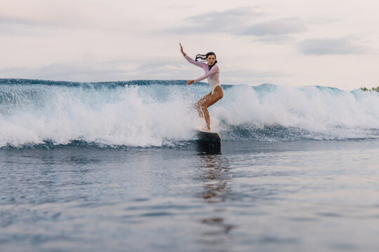 Surfer woman riding on foam wave on surfboard, during surfing