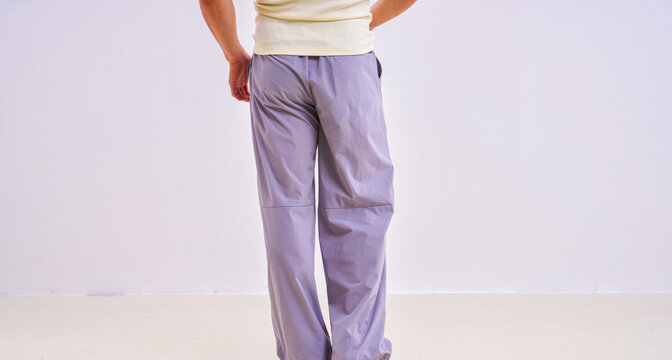                               Asian athletic male model in light purple loose casual trousers, studio apparel photo on plain background 