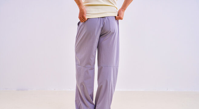                               Asian athletic male model in light purple loose casual trousers, studio apparel photo on plain background 
